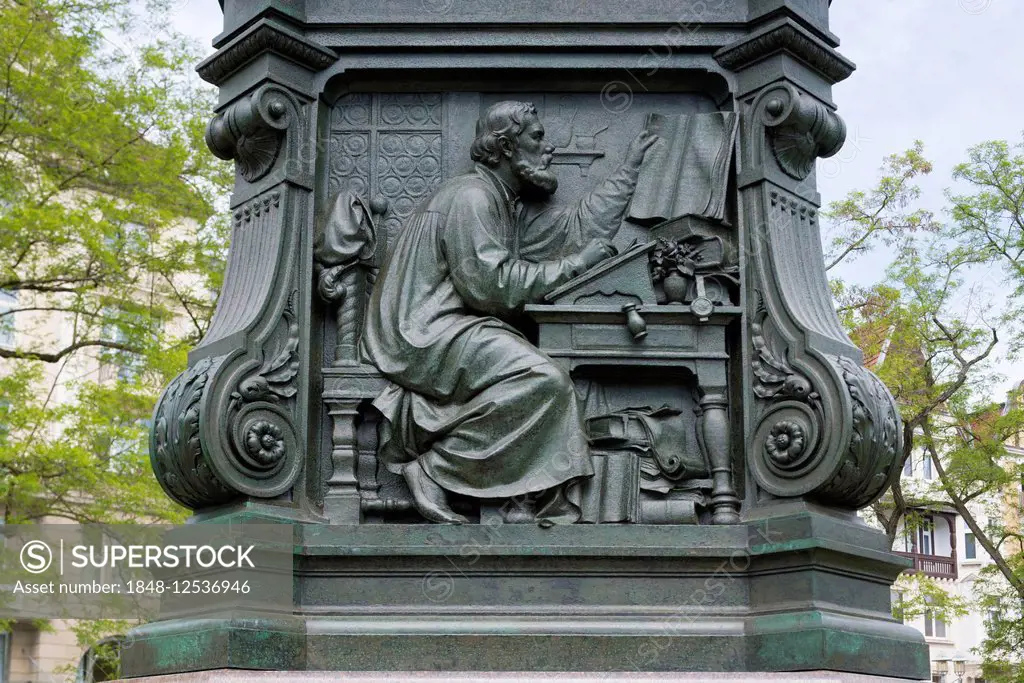 Martin Luther monument, detail, relief, Luther translating the Bible, 1895, by sculptor Adolf von Donndorf, Eisenach, Thuringia, Germany