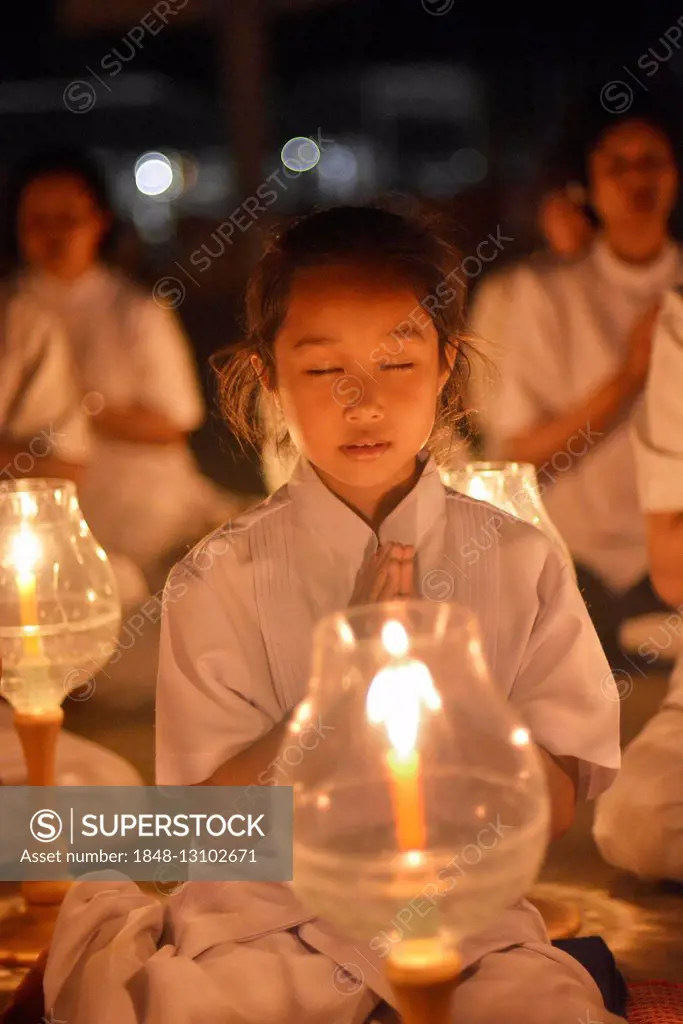 Young girl praying, candlelight, lights, Wat Phra Dhammakaya temple, Bangkok, Thailand