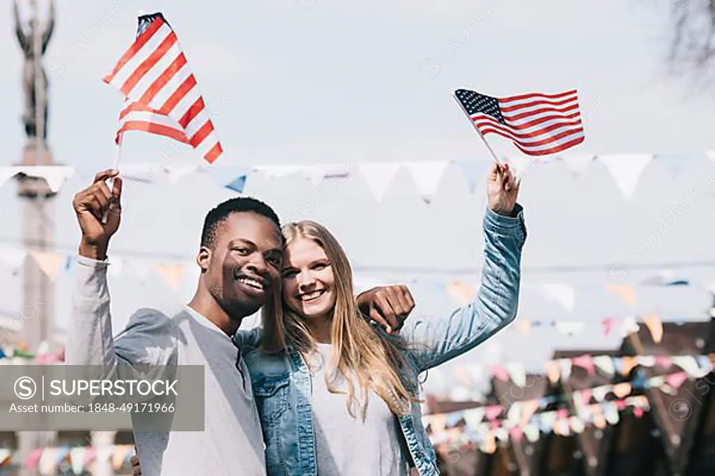 Multiethnic friends holding american flags outstretched hands