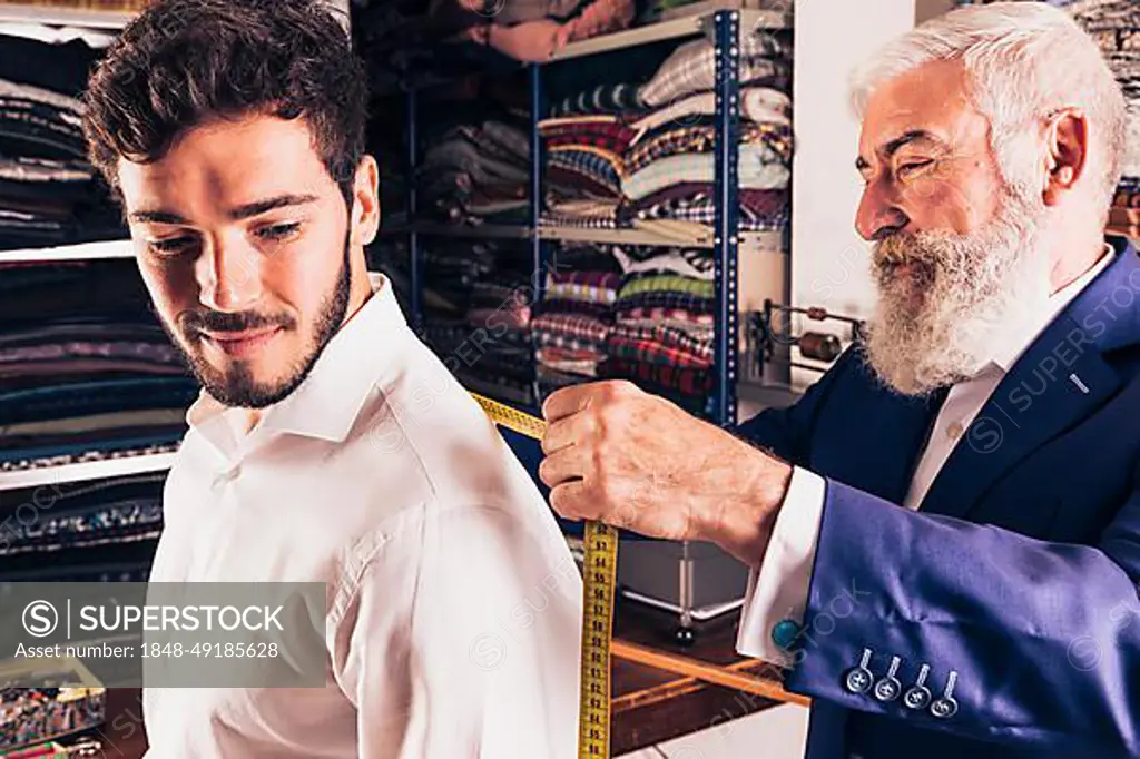 Senior male fashion designer taking measurement his customer shop