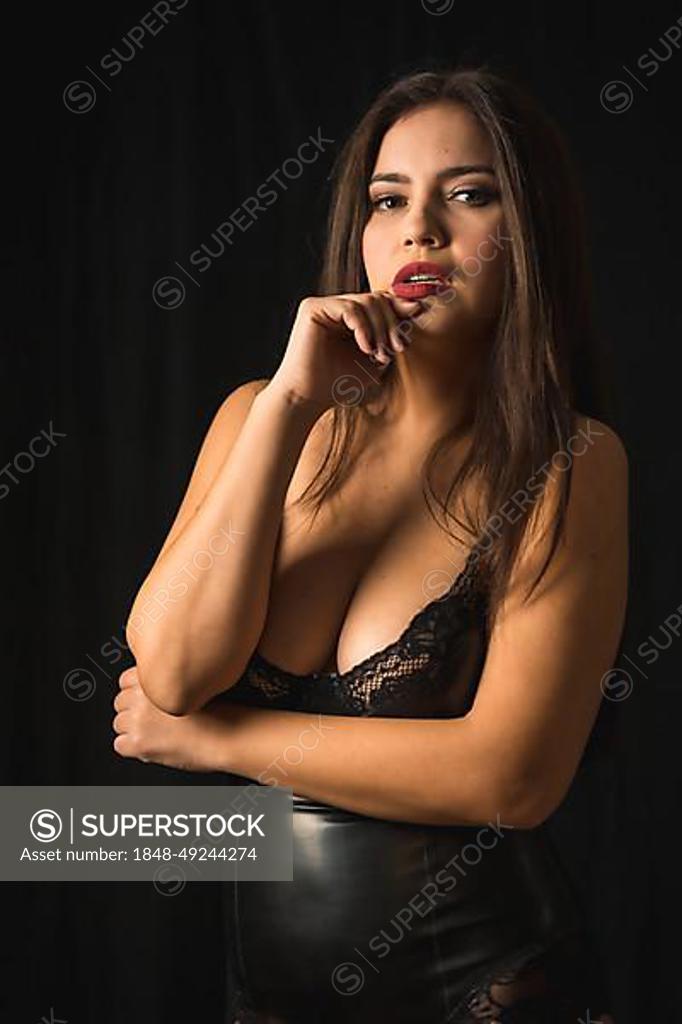 Latin woman with black hair wearing latex underwear, photographed in a  studio with a black background. Photo of the model looking at the camera -  SuperStock