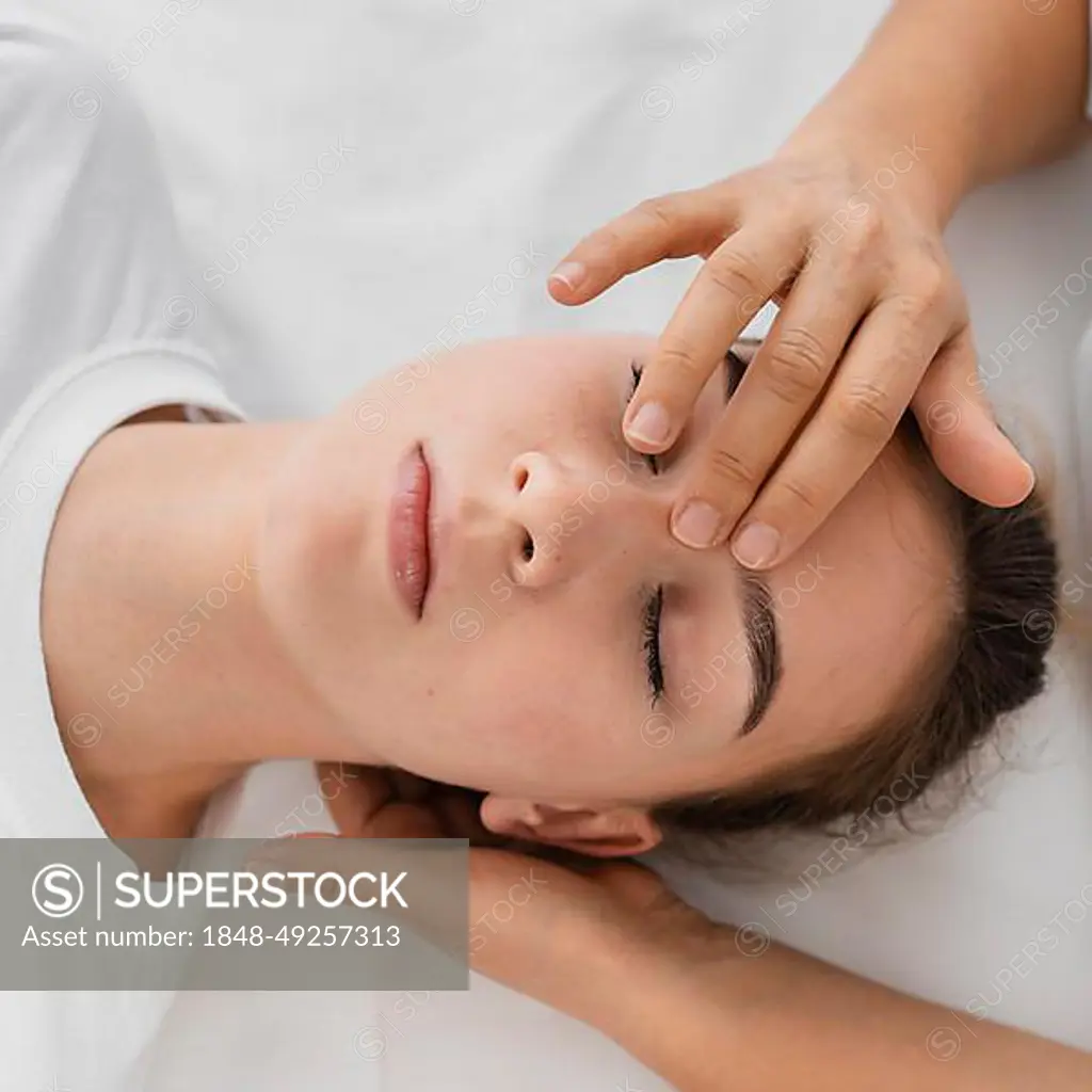 Osteopathist treating patient by massaging her face