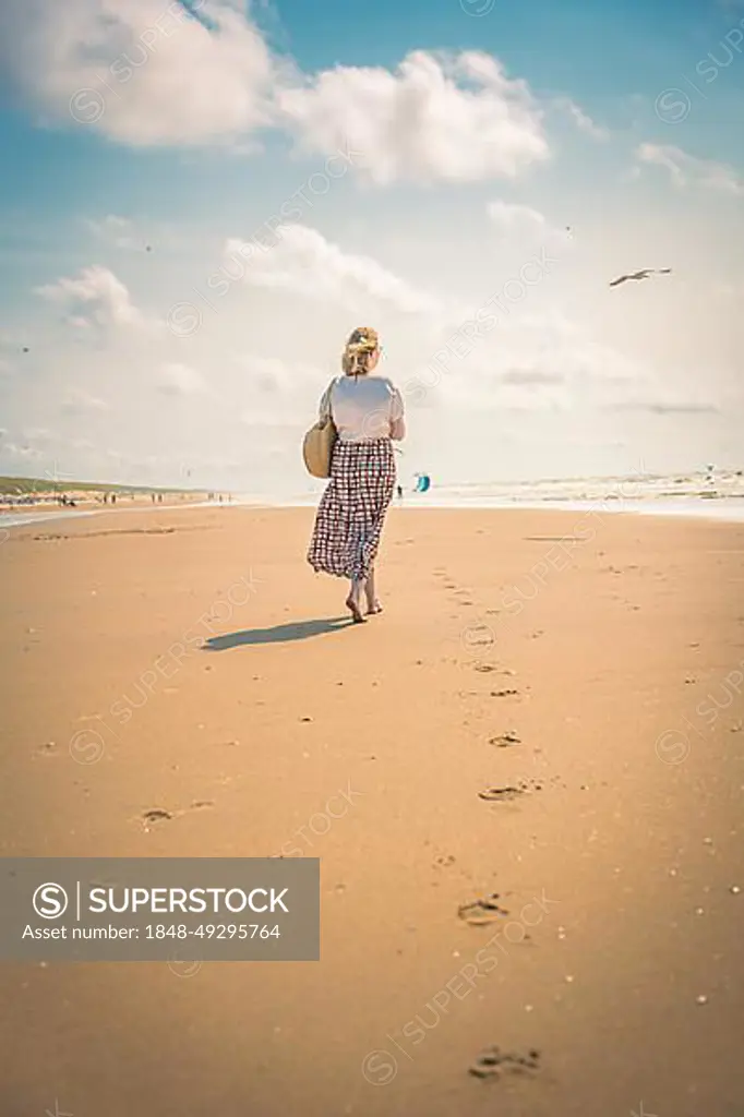 Tourist barefoot with skirt on sandy beach, Zandvoort, Netherlands