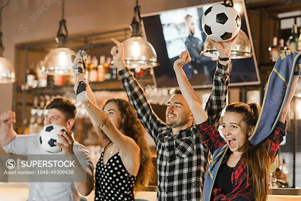 Group friends watching sport together celebrating victory bar