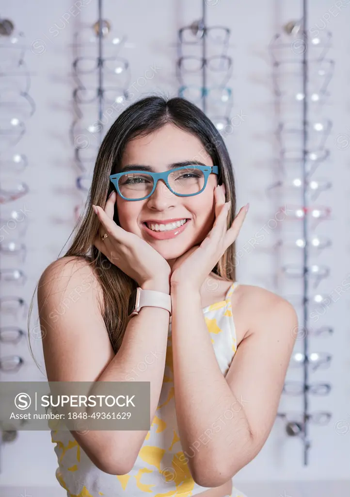 Portrait of a happy female customer wearing glasses in an eyewear store. Smiling girl wearing glasses in an eyeglass store