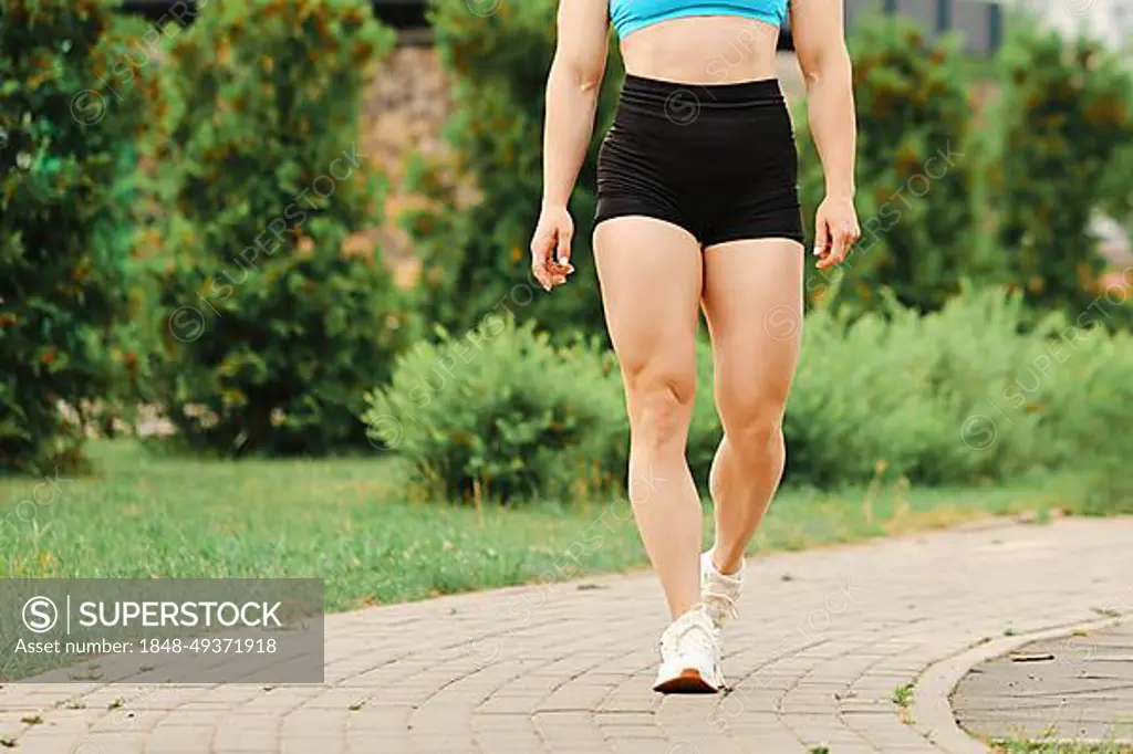Muscular legs of female bodybuilder walking - SuperStock