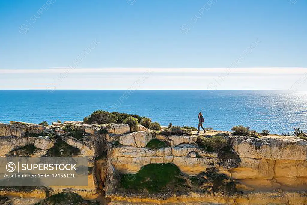 A woman on the top of cliffs at Marinha Beach in Algarve, south Portugal