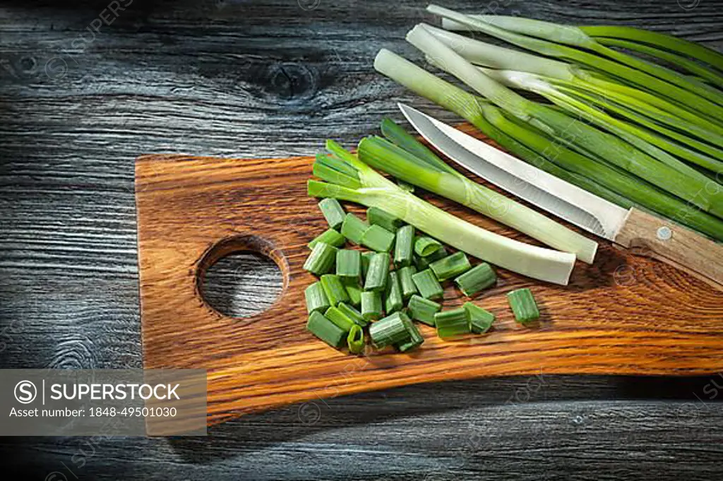 Chopped onions and kitchen knife on wooden cutting board vintage wood background