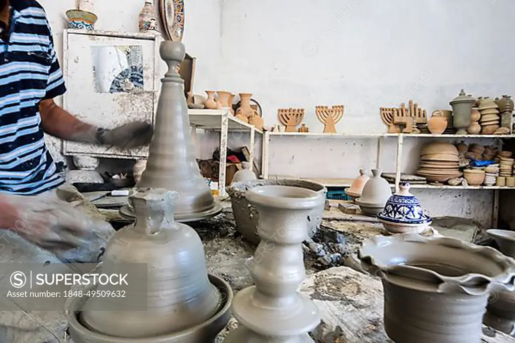 Skillful potter forming a vessel out of gray clay in a pottery