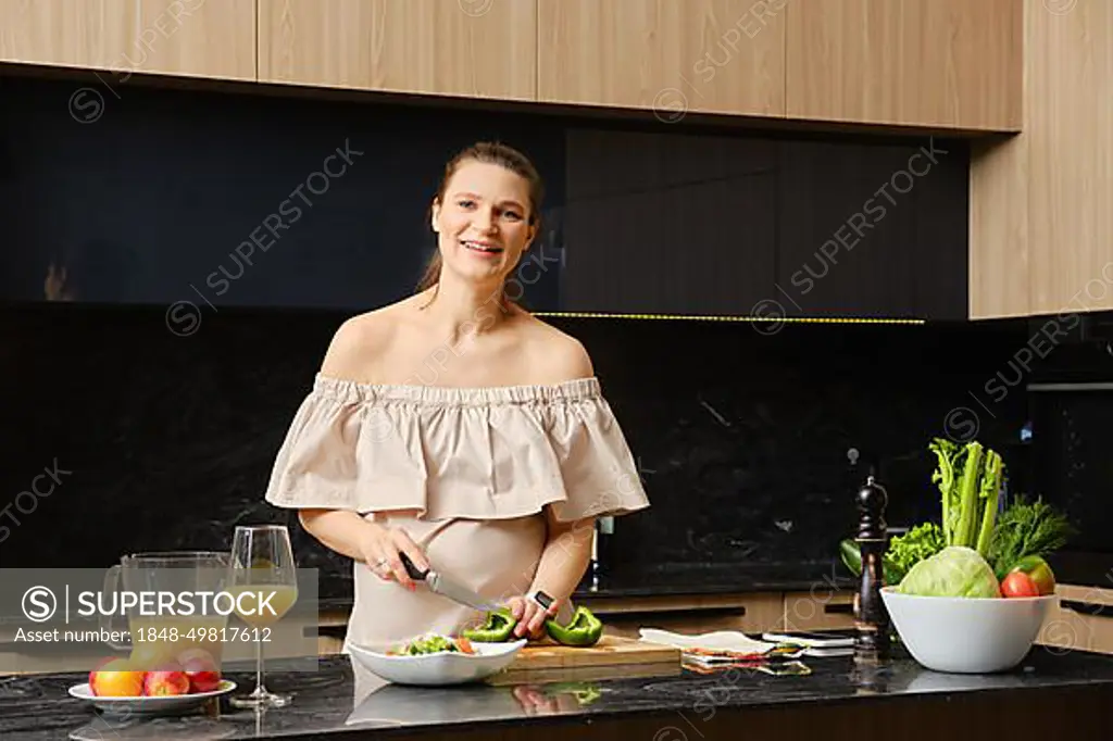 Happy pregnant woman making healthy food at home. Concept of healthy lifestyle