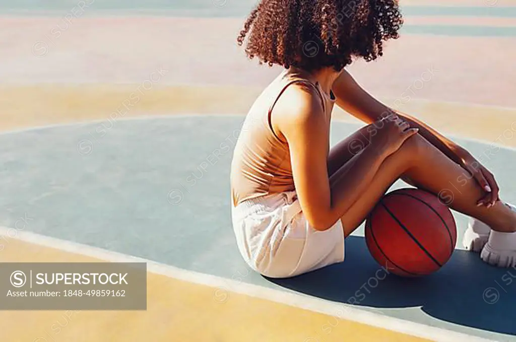 Mixed-race young smiling female outdoors and having fun. Stylish cool teen girl gathering at basketball court, playing basketball outdoors