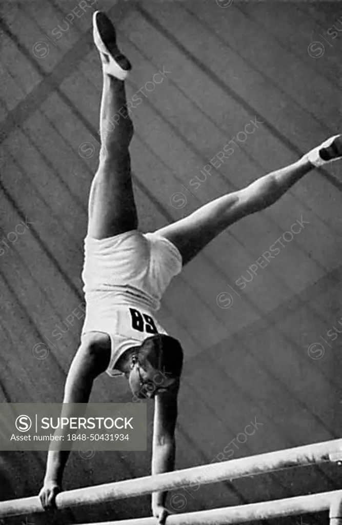 Gymnastics, apparatus gymnastics, the German gymnast Kaete Sohnemann does a handstand with straddled legs on the parallel bars