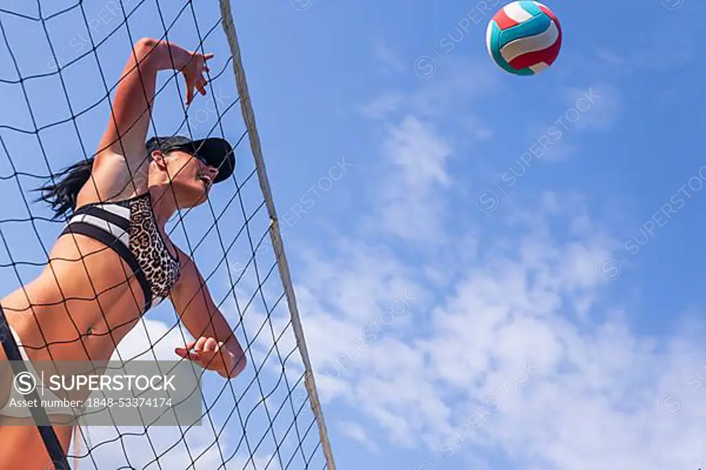 A female athlete plays volleyball on a sandy court during a competition