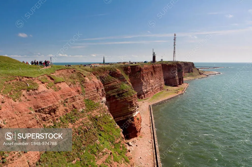 The prominent steep red sandstone cliffs of Heligoland with its lighthouse and a radio tower, Helgoland, Schleswig-Holstein, Germany, Europe