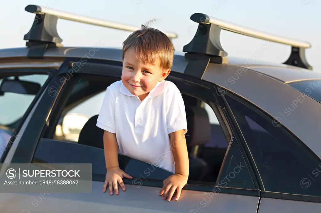 Portrait of a smiling little boy at beach in the car. Holiday and travel concept