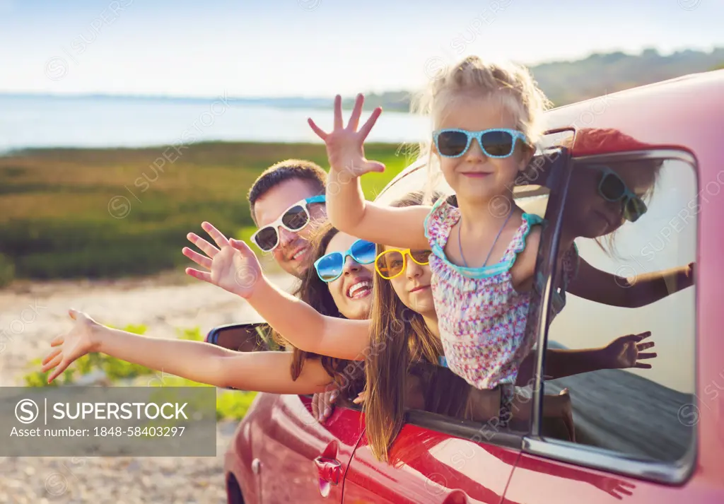 Portrait of a smiling family with two children at beach in the car. Holiday and travel concept