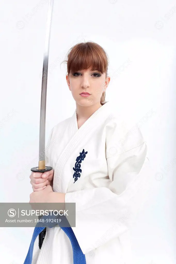 Young woman in a karate suit holding a sword, saber