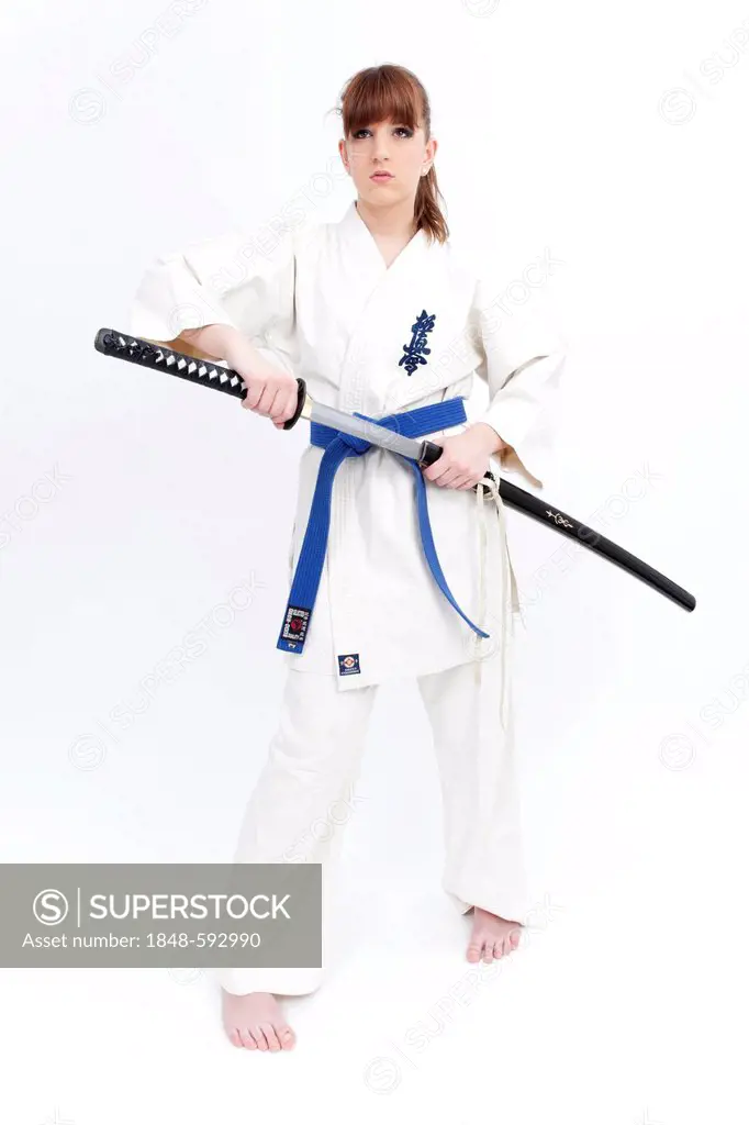 Young woman in a karate suit drawing a sword, saber