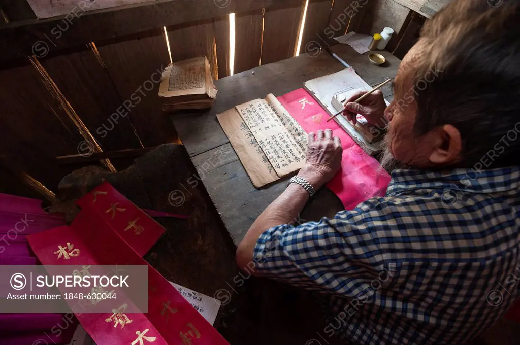 Elderly Chinese man sitting at a desk, ethnic minority, practicing ancient Chinese calligraphy, Northern Thailand, Thailand, Asia