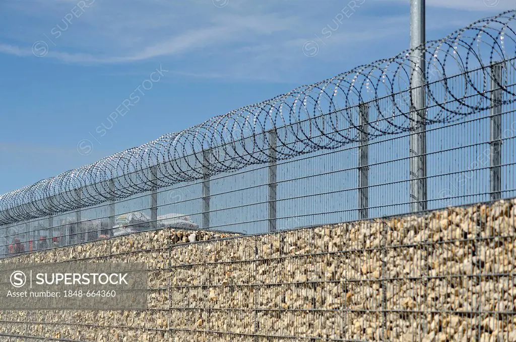 Noise barrier and safety fence with barbed wire in front of the storage yard of a building centre, Eckental, Middle Franconia, Bavaria, Germany, Europ...