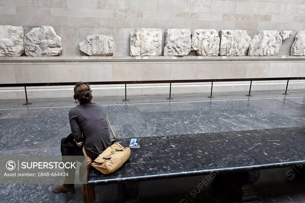 Young museum visitor with audio guide looking at the Elgin Marbles, marble reliefs from the Athens Parthenon, British Museum, London, England, United ...