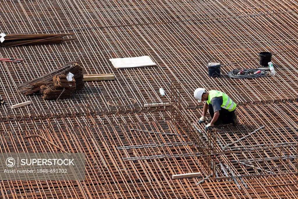 Construction worker installing steel rebar beams for reinforced concrete, building site