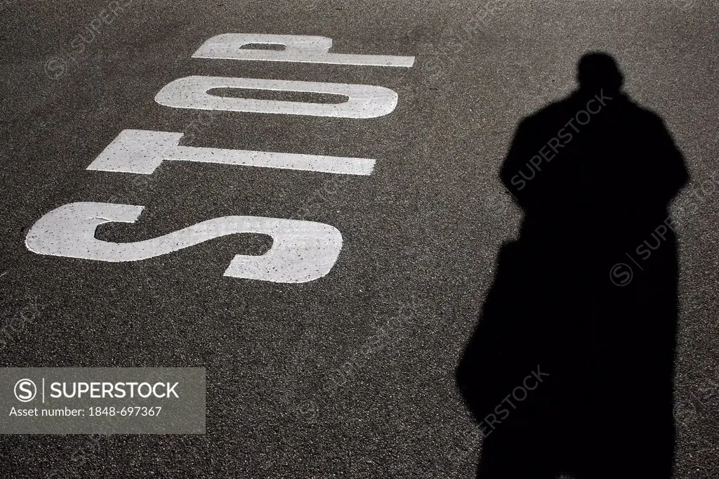 Road markings, ground markings, stop notice on asphalt, shadow of a person