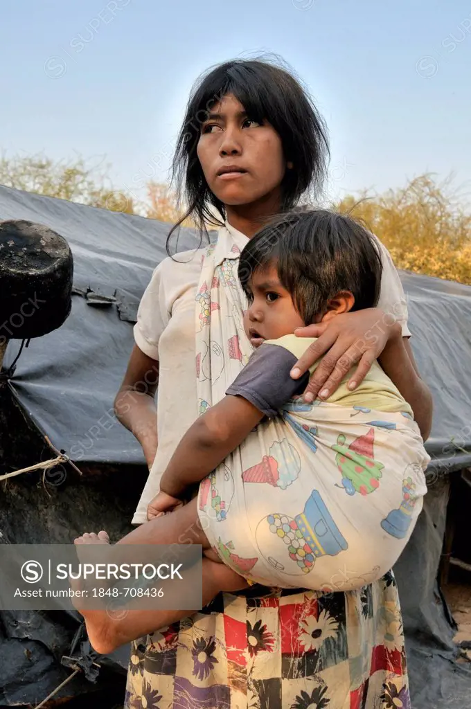 Young indigenous mother from the Wichi Indians tribe carrying a child, Zapota, Gran Chaco, Salta Argentina, South America