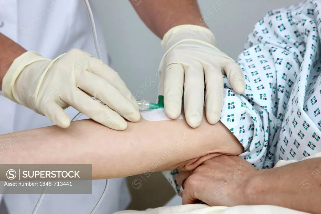 Nurse putting a patient in a hospital bed on a drip infusion, hospital