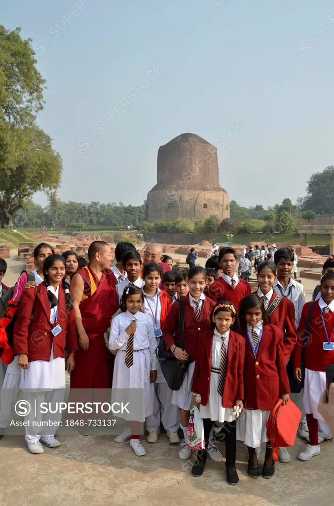 Pupils of an Indian school class, boys and girls, with Tibetan monks and a Rinpoche visiting the Dhamekh Stupa, Game Park of Isipatana, Sarnath, Uttar...