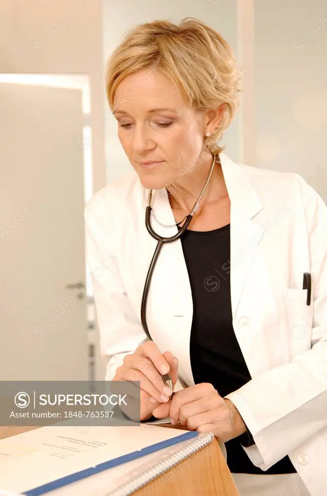 A female doctor in a white coat with stethoscope is standing at a reception desk