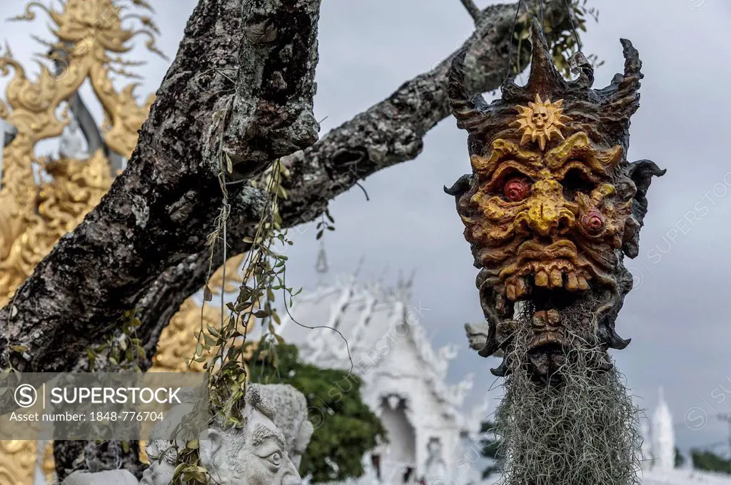 A mask hanging on a tree, at the Wat Rong Khun temple or The White Wat, a Buddhist-Hindu temple