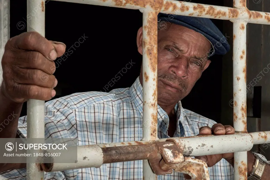 A former prisoner standing behind a door with iron bars, former Tarrafal concentration camp or Campo do Tarrafal, Tarrafal, Santiago, Cape Verde