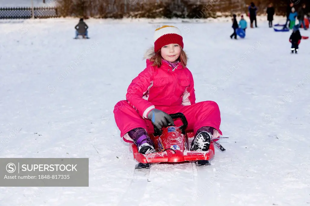 Girl sitting on a sled, Baden Wuerttemberg, Germany