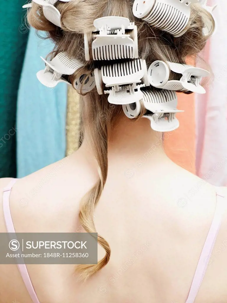 Woman wearing curlers with a single strand of hair hanging down