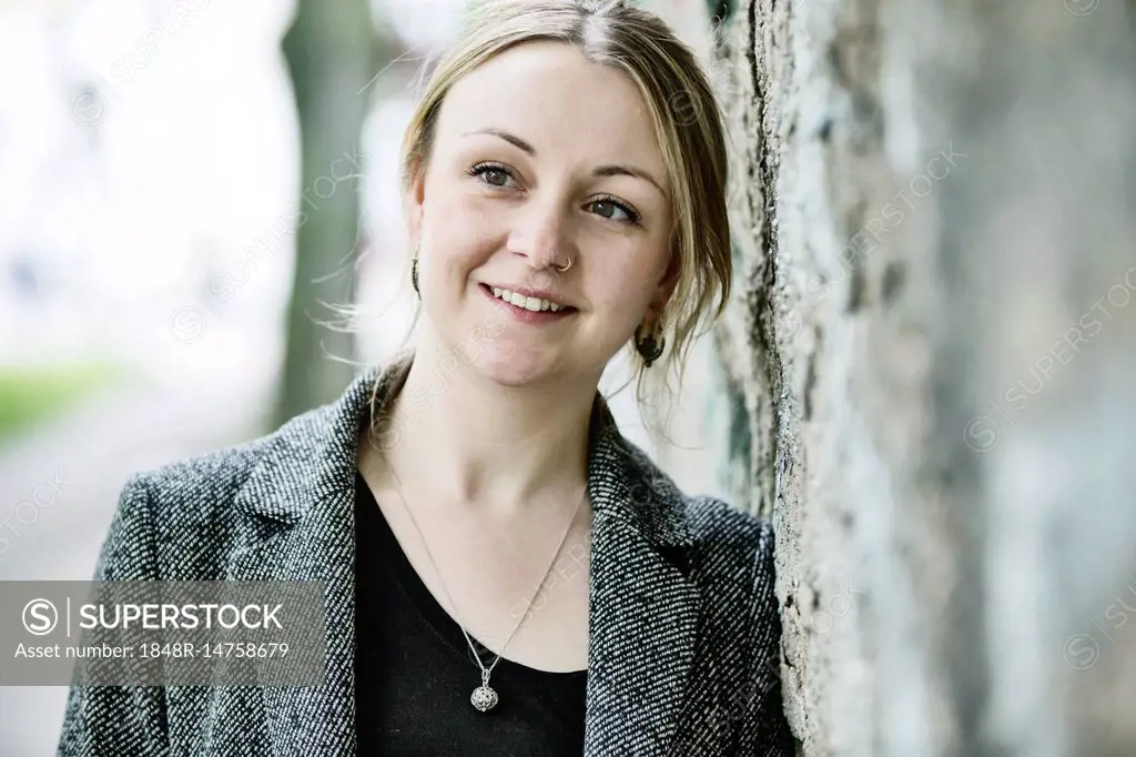 Young woman leaning against a wall, portrait, Germany