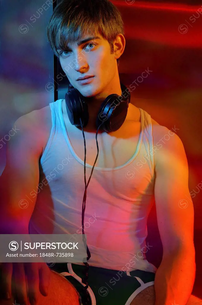 Young man in underwear with headphones in colorful light