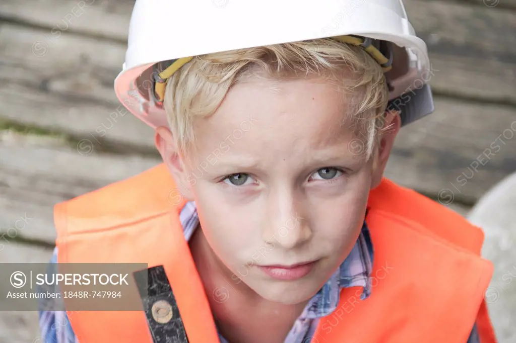 Boy dressed as a construction worker with a hard hat, a safety vest and a hammer