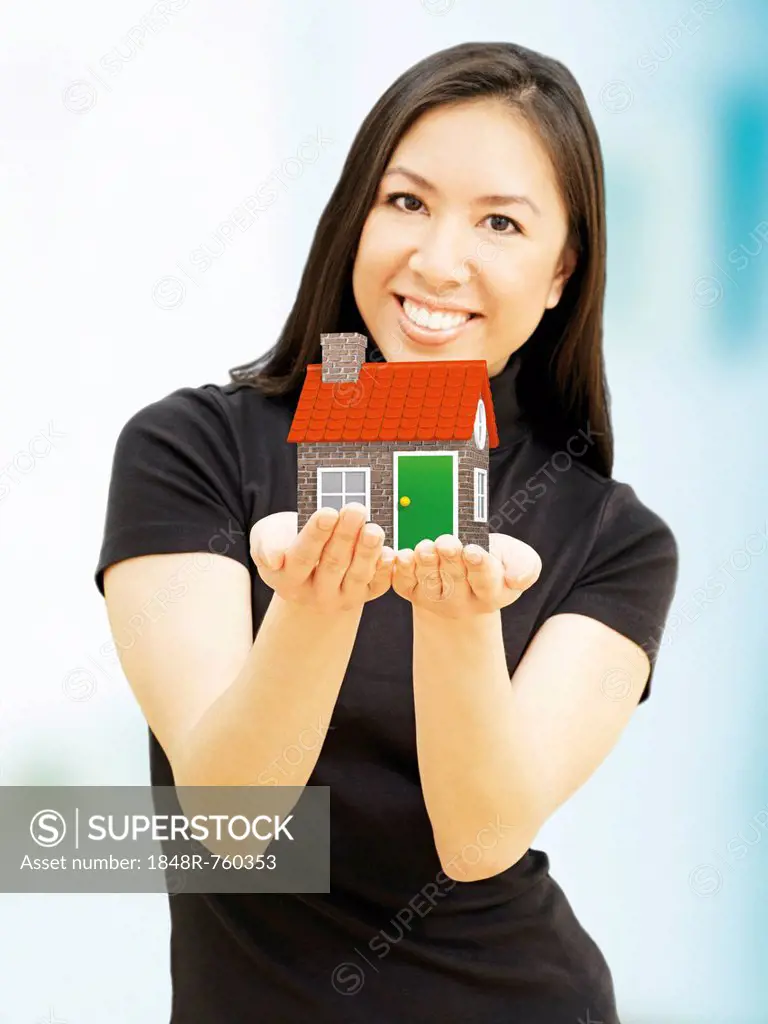 Young woman holding a miniature house