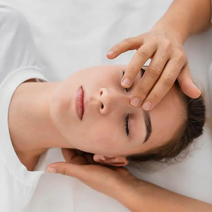 Osteopathist treating patient by massaging her face