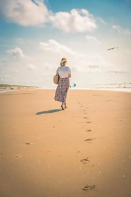 Tourist barefoot with skirt on sandy beach, Zandvoort, Netherlands