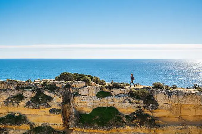 A woman on the top of cliffs at Marinha Beach in Algarve, south Portugal