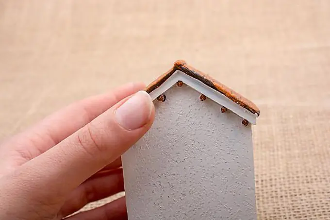 Model house and a hand on a light brown color background