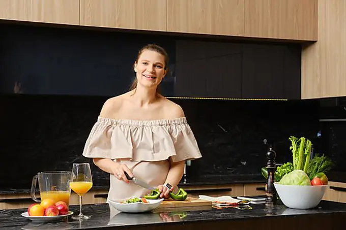 Happy pregnant woman making healthy food at home. Concept of healthy lifestyle