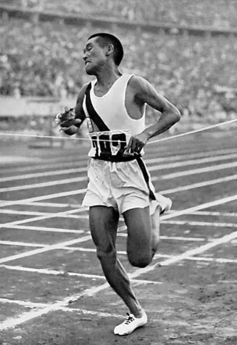 Marathon runner Kitei Son (Japan) is the first to tear the finishing ribbon in the Olympic Stadium after 42 km, marathon race