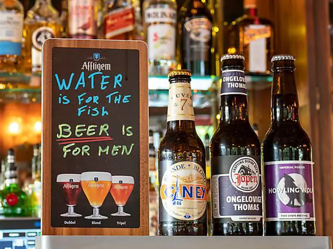 Different beer bottles and funny sign in a bar, Amsterdam, Kingdom of the Netherlands