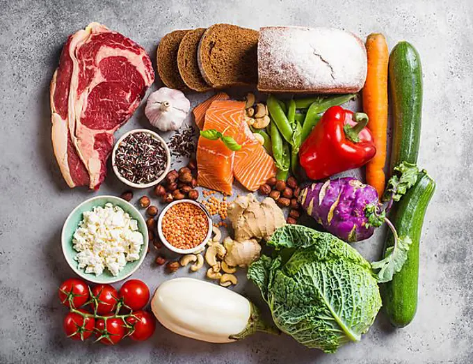 Assortment of healthy balanced food composition: meat, fish, vegetables, bread, cereals, beans, stone background. Raw ingredients for cooking healthy meal, good for diet, clean eating concept