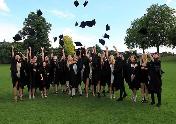 Graduates in gowns throwing their mortarboards into the air, Goldsmiths, University of London, England, UK