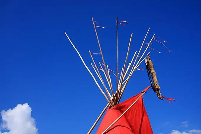 Red Indian tent with animal skins, detail, background blue sky and clouds