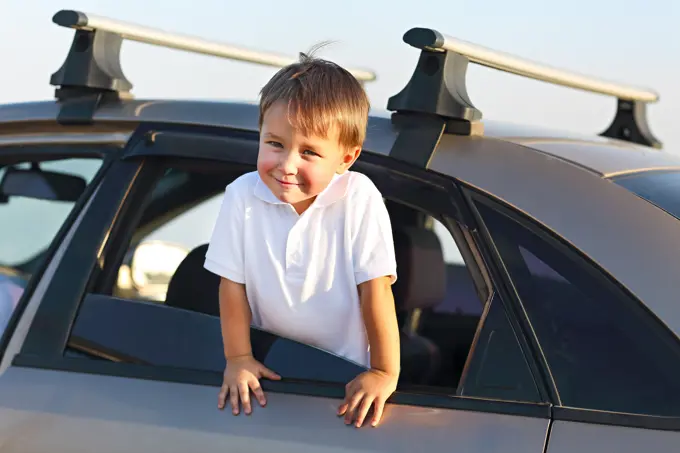 Portrait of a smiling little boy at beach in the car. Holiday and travel concept